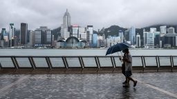 Two men use umbrellas on Kowloon's Tsim Sha Tsui waterfront that faces Victoria Harbour and the Hong Kong Island skyline (back), after Typhoon Higos swept past overnight in Hong Kong on August 19, 2020. 