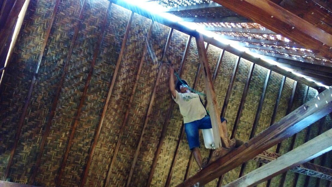 A local artisan mold-proofs the bedek (traditional rattan-thatch ceiling).