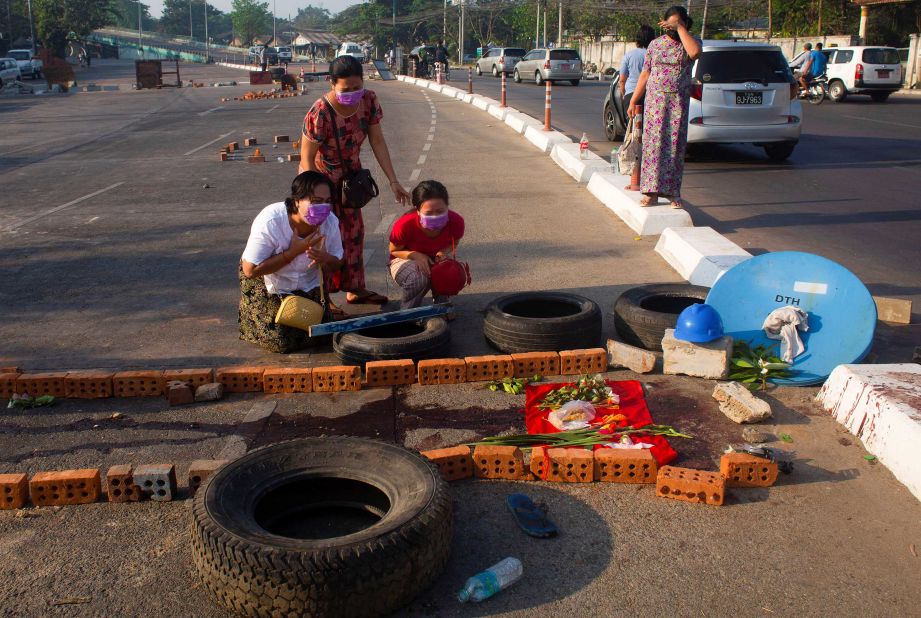 People cry in Yangon on March 4, near a spot where a family member was killed while protesting.