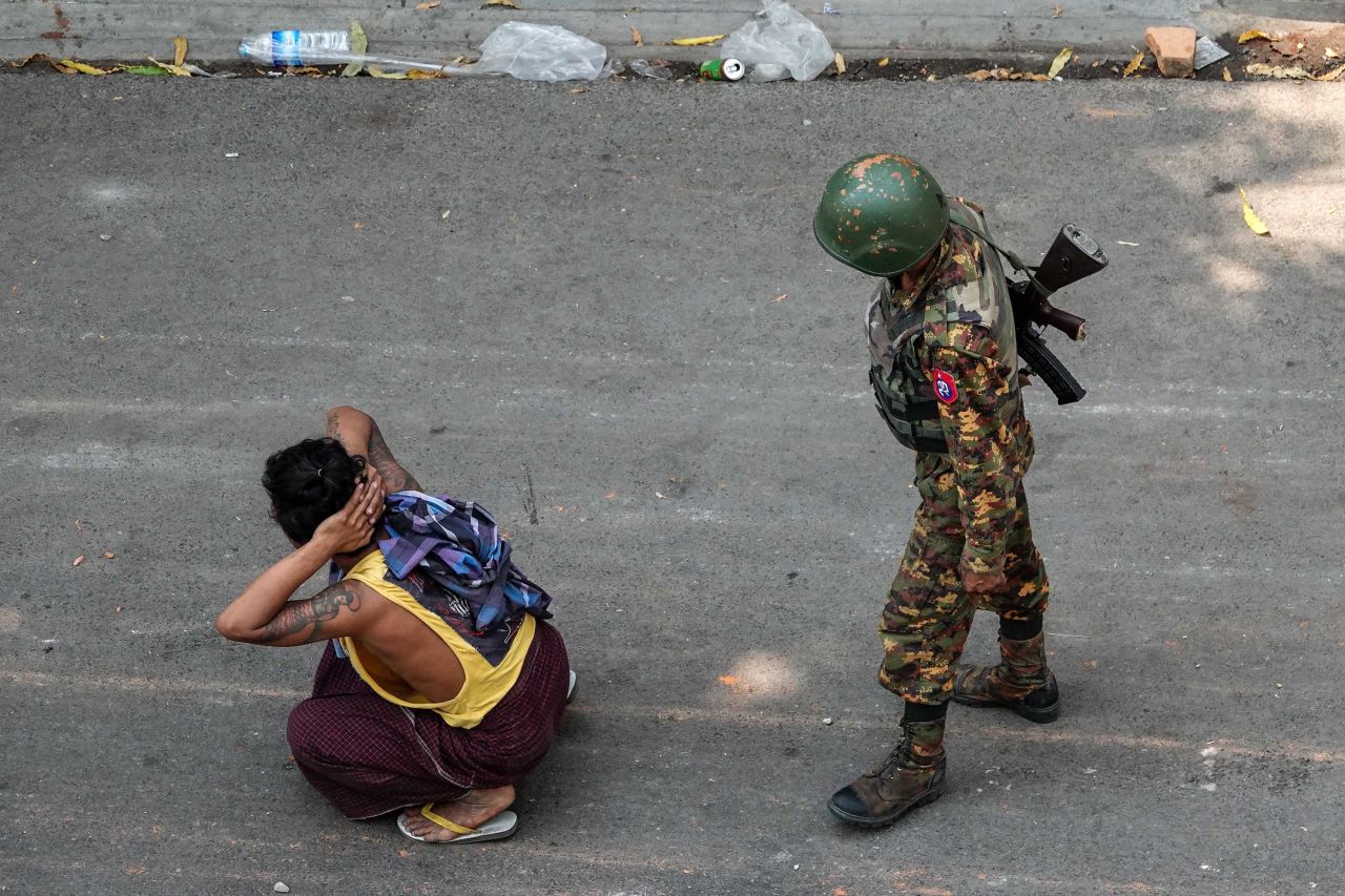 A soldier stands next to a detained man during a demonstration in Mandalay on March 3.