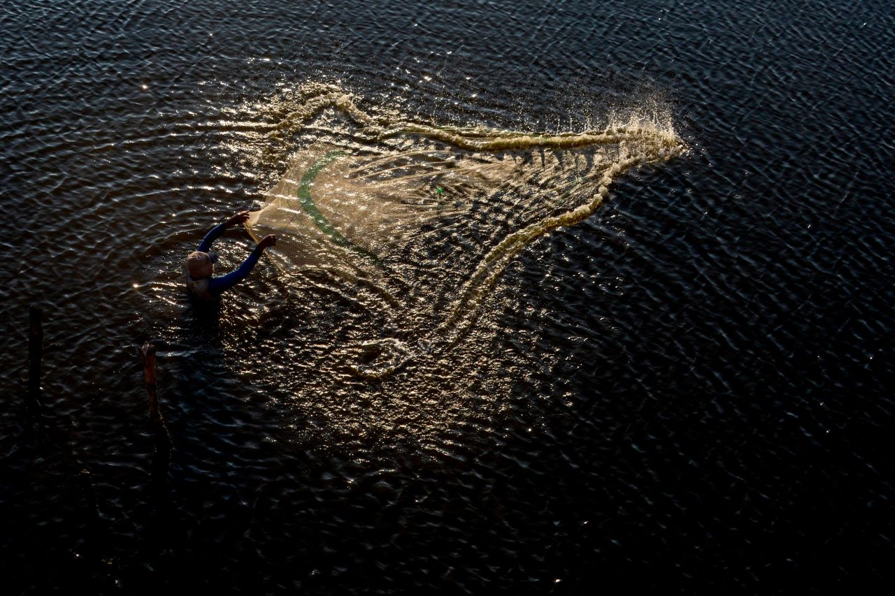 A man spreads a net to fish in shallow waters as the sun sets in Banda Aceh, Indonesia, on Sunday, February 28.