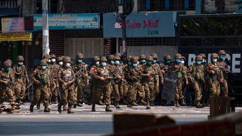 Military soldiers walk down a street with weapons that contain live ammunition after clashes with protesters on March 3 in Yangon, Myanmar. 