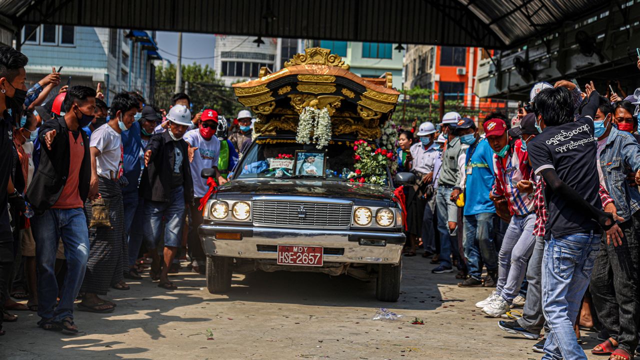 People pay respects as the hearse carrying the coffin of Ma Kyal Sin drives on the street.