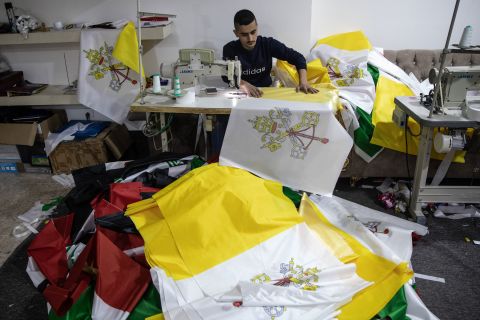 A man sews the flag of Vatican City at a printing house in Erbil on Thursday.
