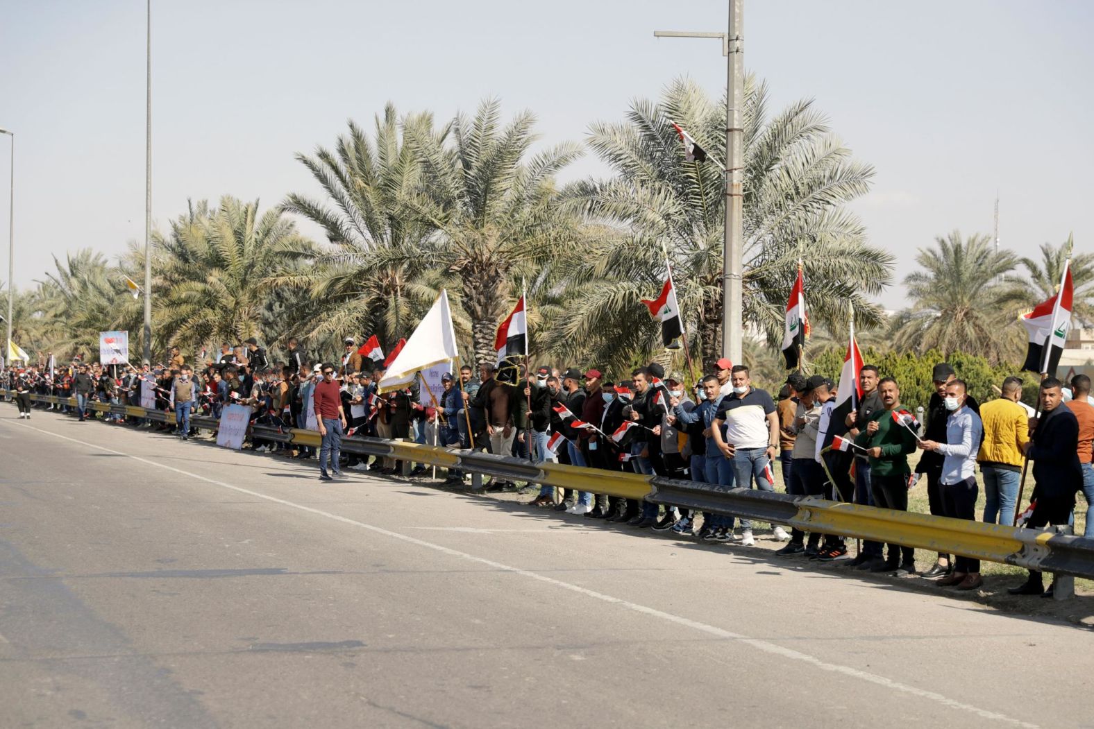 People in Baghdad stand by a road as they wait for Pope Francis to pass on Friday.