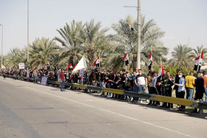 People in Baghdad stand by a road as they wait for Pope Francis to pass on Friday.