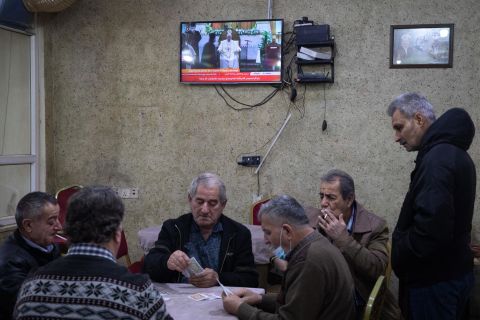 People play cards at a tea house in Erbil, Iraq, as a television shows live footage of the Pope's visit on Friday.