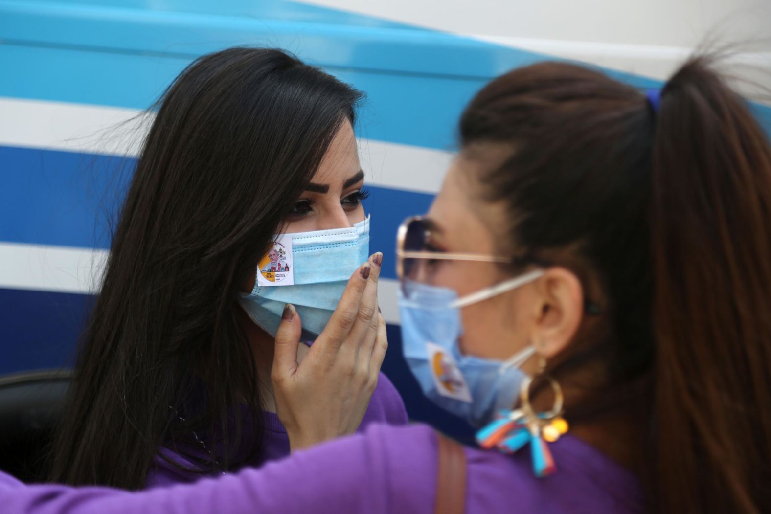 People wear face masks with pictures of Pope Francis on Friday.