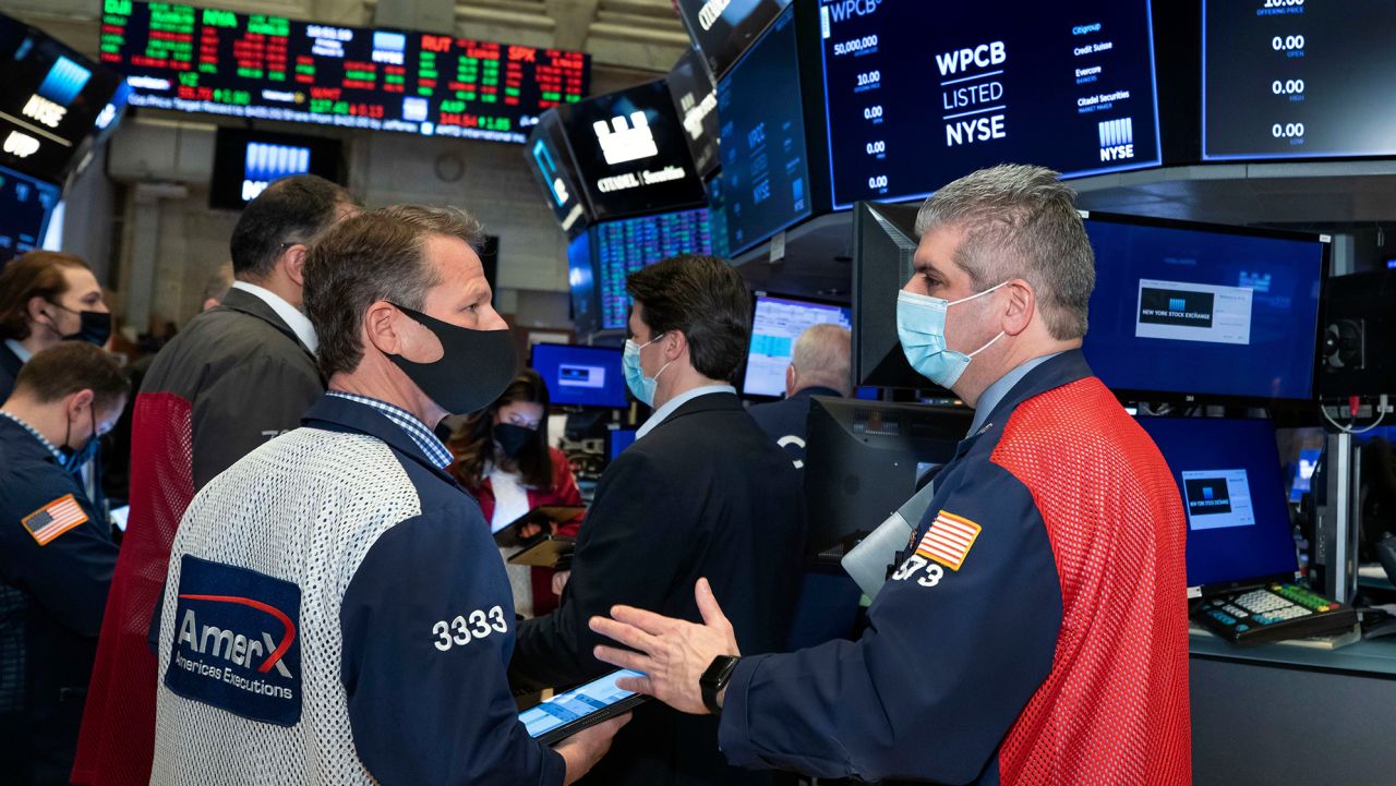 In this photo provided by the New York Stock Exchange, traders Robert Charmak and John Panin, foreground left and right, work on the floor, Friday, March 5, 2021, in New York. Stocks are swerving through another rocky ride Friday, as investors struggle to figure out what an encouraging report on the economy and the recent march higher for bond yields should mean for the market. (Nicole Pereira/New York Stock Exchange via AP)