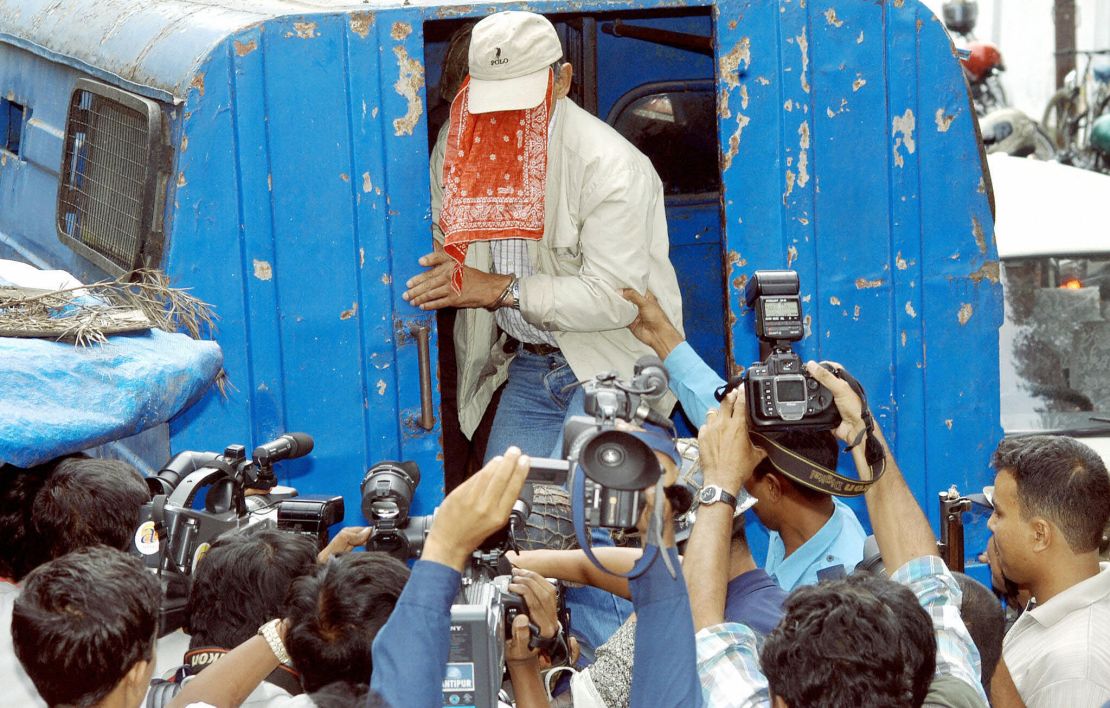 Sobhraj, face covered, is swarmed by photographers outside Kathmandu district court on September 22, 2003. 