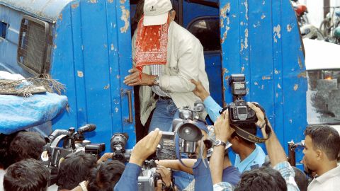 Sobhraj, face covered, is swarmed by photographers outside Kathmandu district court on September 22, 2003. 