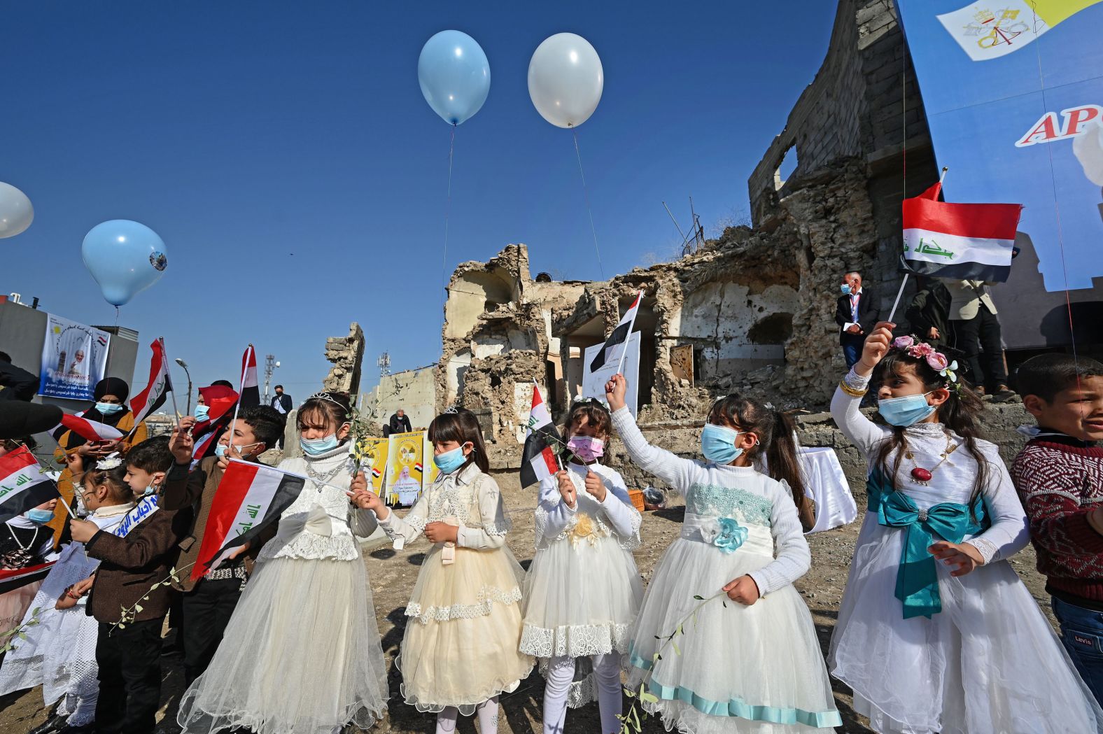 Children in Mosul wave national flags Sunday near the ruins of al-Tahira-l-Kubra, the Syriac Catholic Church of the Immaculate Conception.