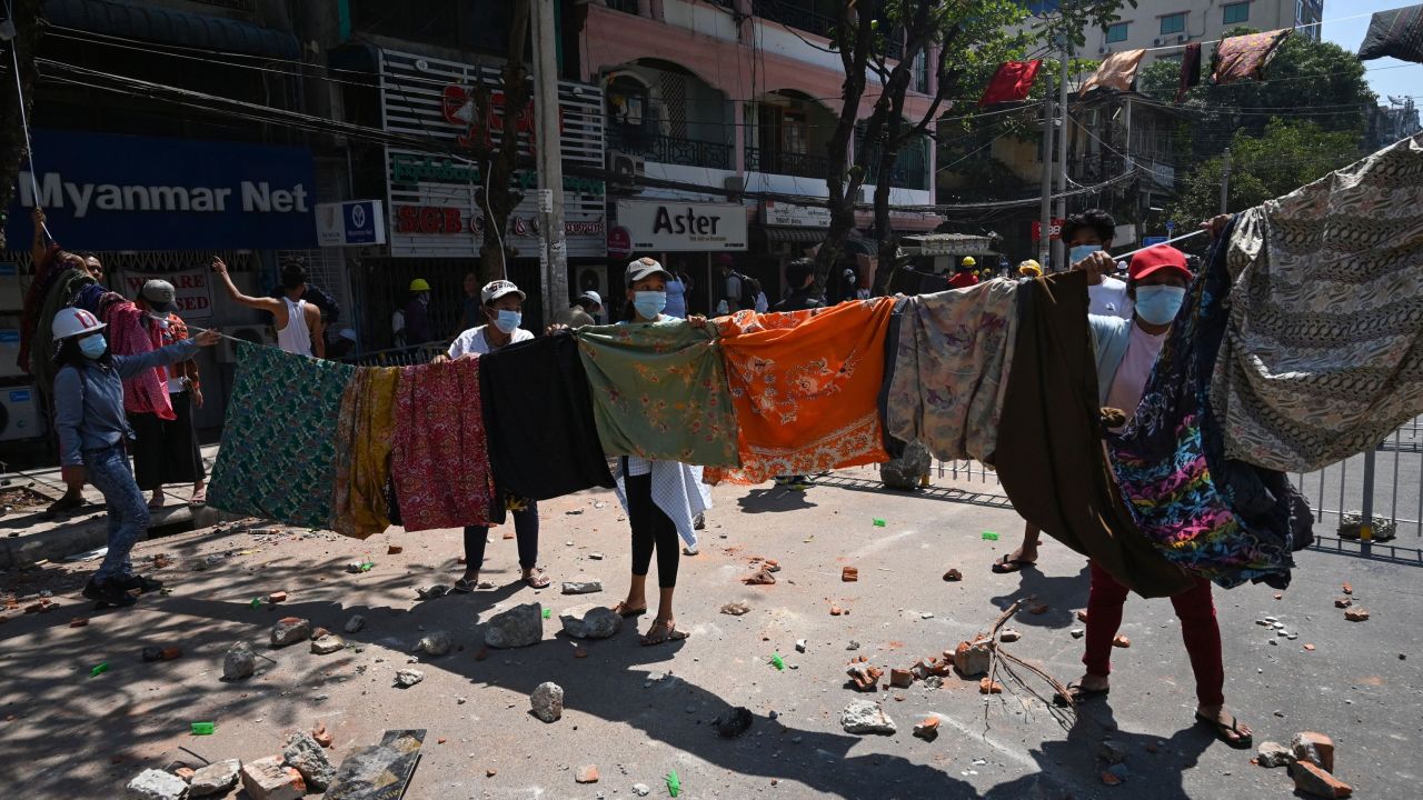Women hang a collection of longyi, a traditional clothing widely worn in Myanmar, across a road during a demonstration against the military coup in Yangon on March 8.