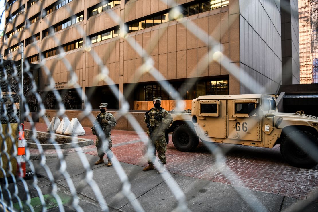 Members of the National Guard and Minnesota Police stand behind a barbed wire fence perimeter surrounding the Hennepin County Government Center in Minneapolis on Monday.