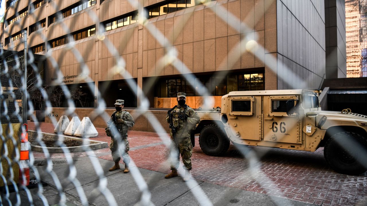 Members of the National Guard and Minnesota Police stand behind a barbed wire fence perimeter surrounding the Hennepin County Government Center in Minneapolis on Monday.
