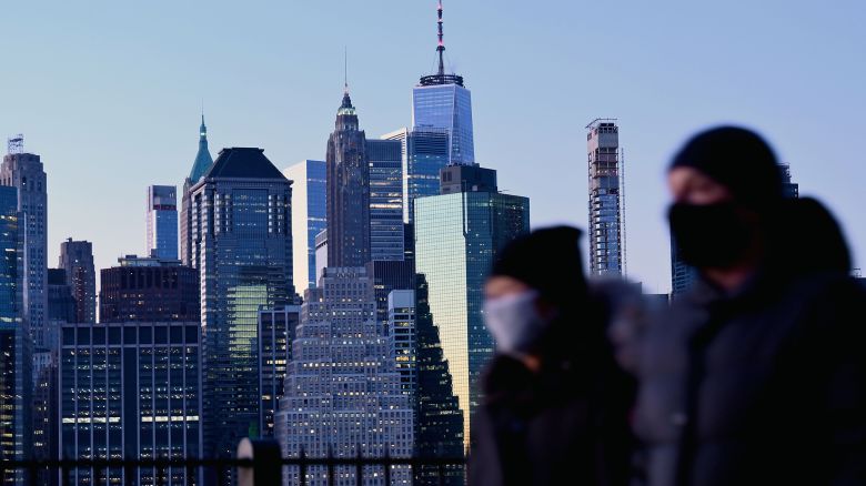 People wearing masks walk during a cold evening on the Brooklyn Promenade on November 18, 2020 in New York City. - US states and cities are imposing a raft of new restrictions, including home confinement, the closure of indoor dining and a limit on gatherings as cases soar across the country. (Photo by Angela Weiss/AFP/Getty Images)