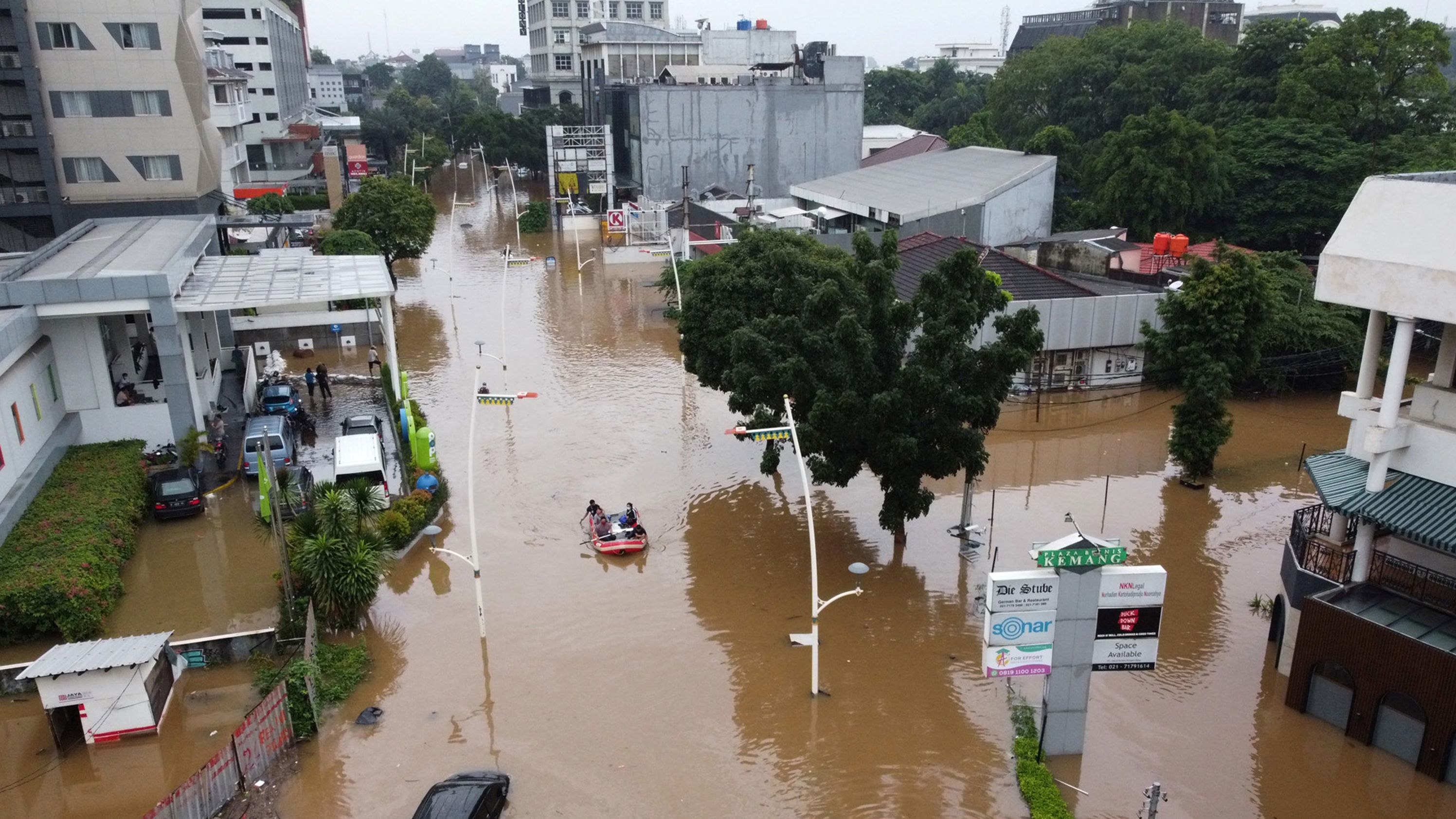 This aerial picture shows people rowing a raft over a flooded road in Jakarta on February 20, 2021, following heavy overnight rains. The combination of so many people and the multitude of rivers has made this city especially prone to relative sea level rise.