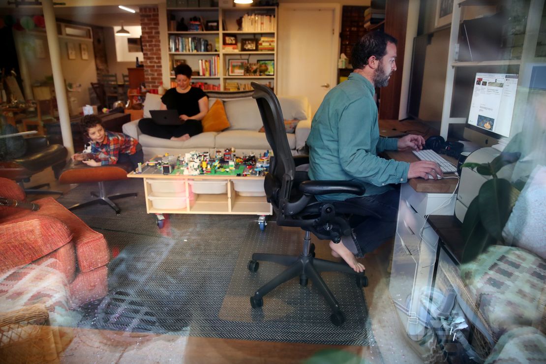 Seth and Nicole Kroll work while their son Louis, 5, entertains himself at their home outside of Boston. 