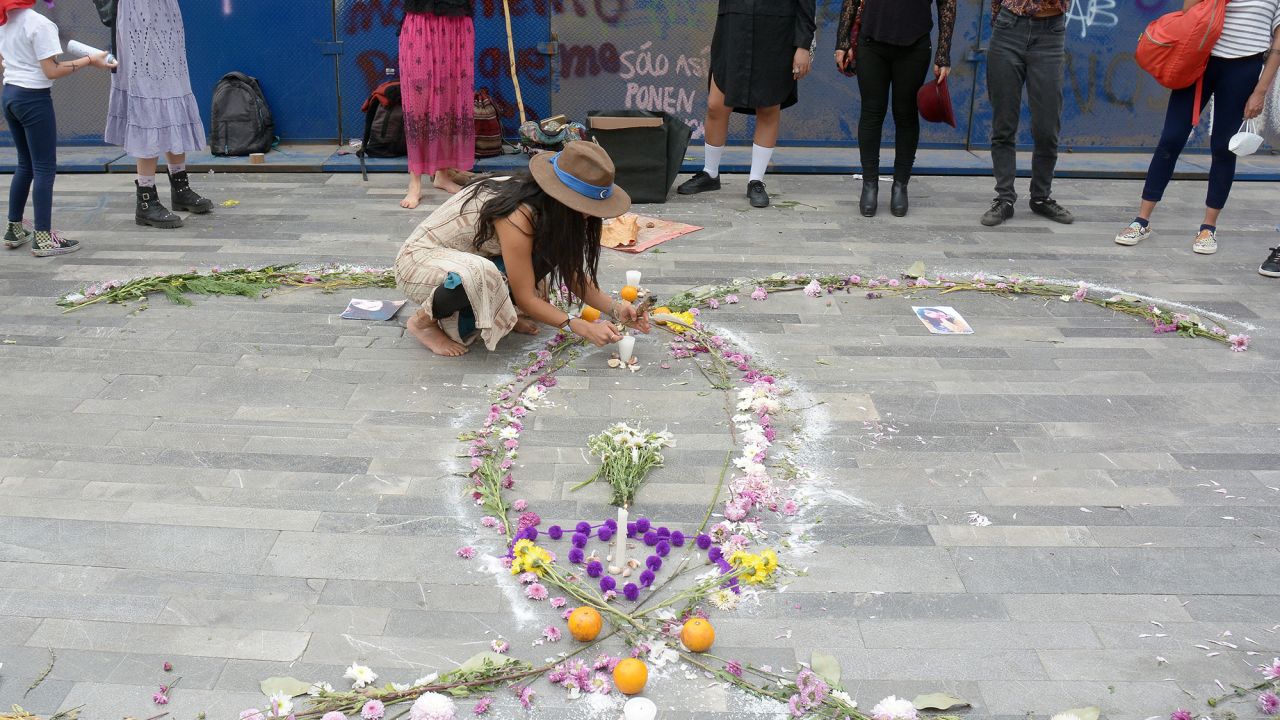 A woman places candles to a mock tombstone, which symbolizes victims of femicides during International Women´s Day protest on March 8, 2021 in Mexico City, Mexico.
