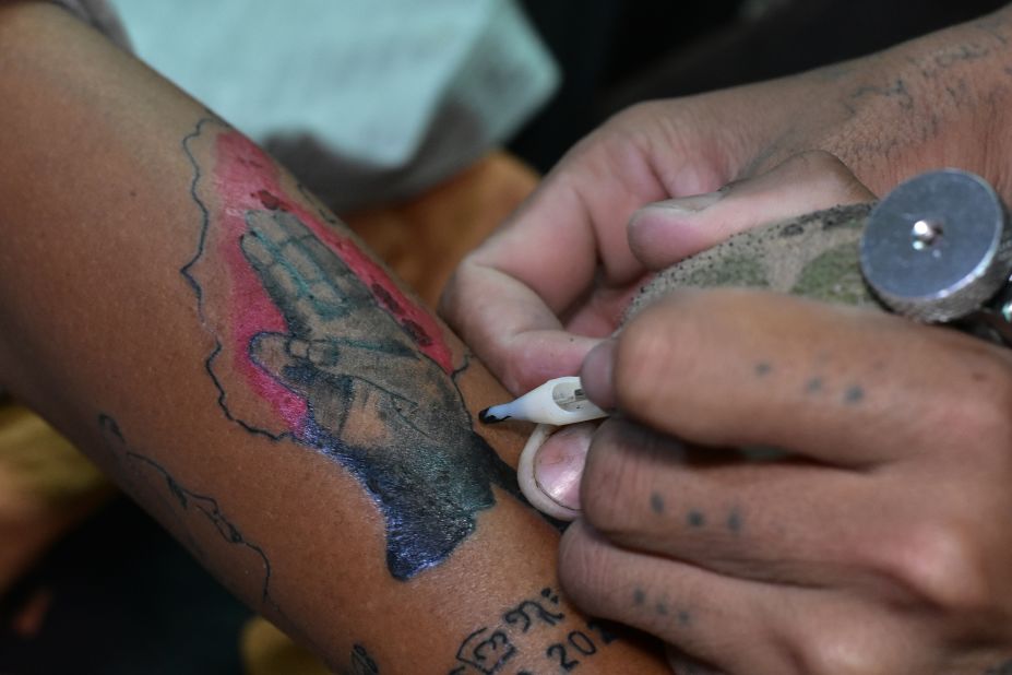 A protester gets a tattoo of the three-finger salute, a popular gesture from "The Hunger Games," seen throughout the protests in Myanmar. Scroll through the gallery for more.
