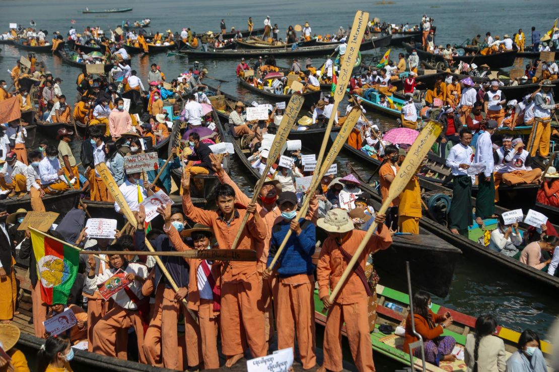 Protesters wearing traditional Shan dress hold up oars and signs as they take part in a demonstration against the Myanmar military coup on Inle lake on February 11, 2021. 