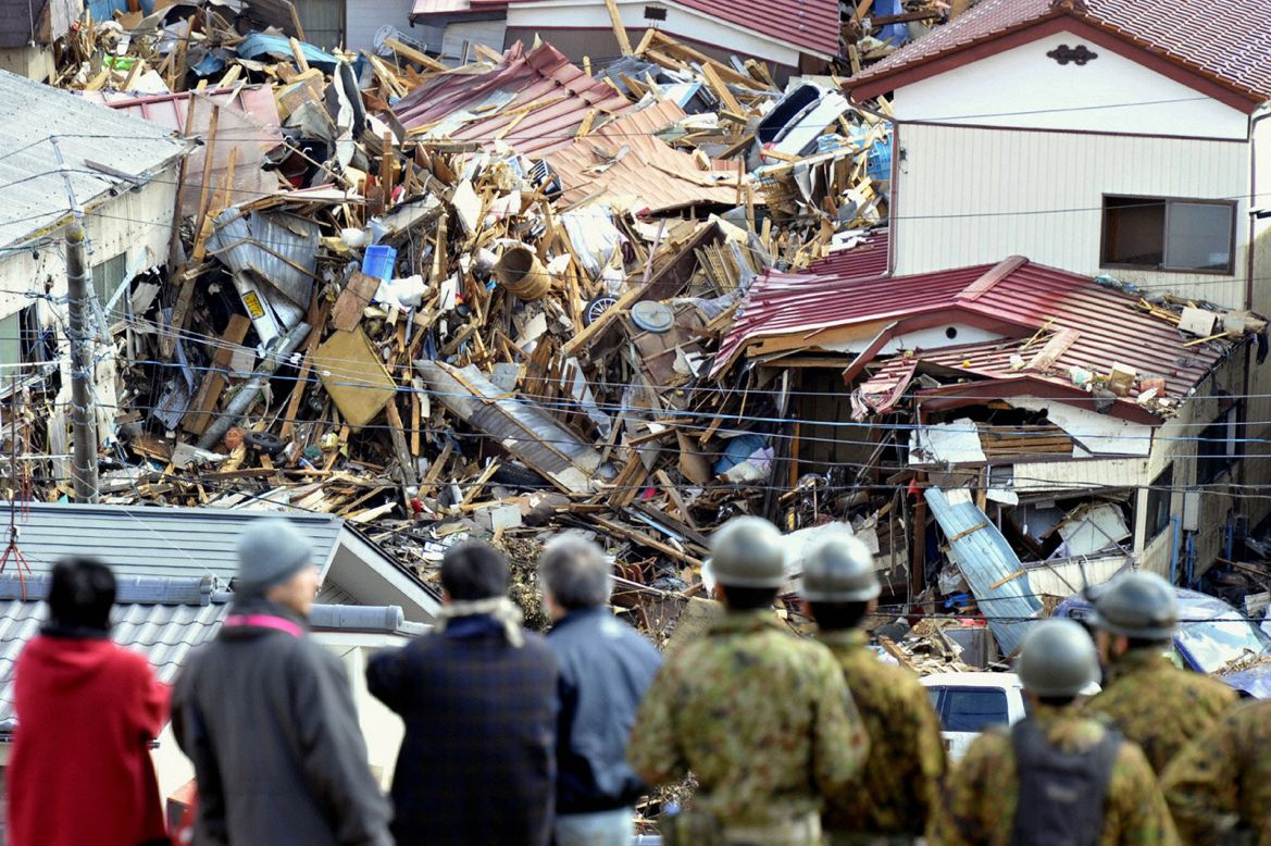 Survivors survey the damage in Kesennuma, Miyagi prefecture, the day after the quake. Ten years on, many people displaced by the disaster are still living in temporary homes.