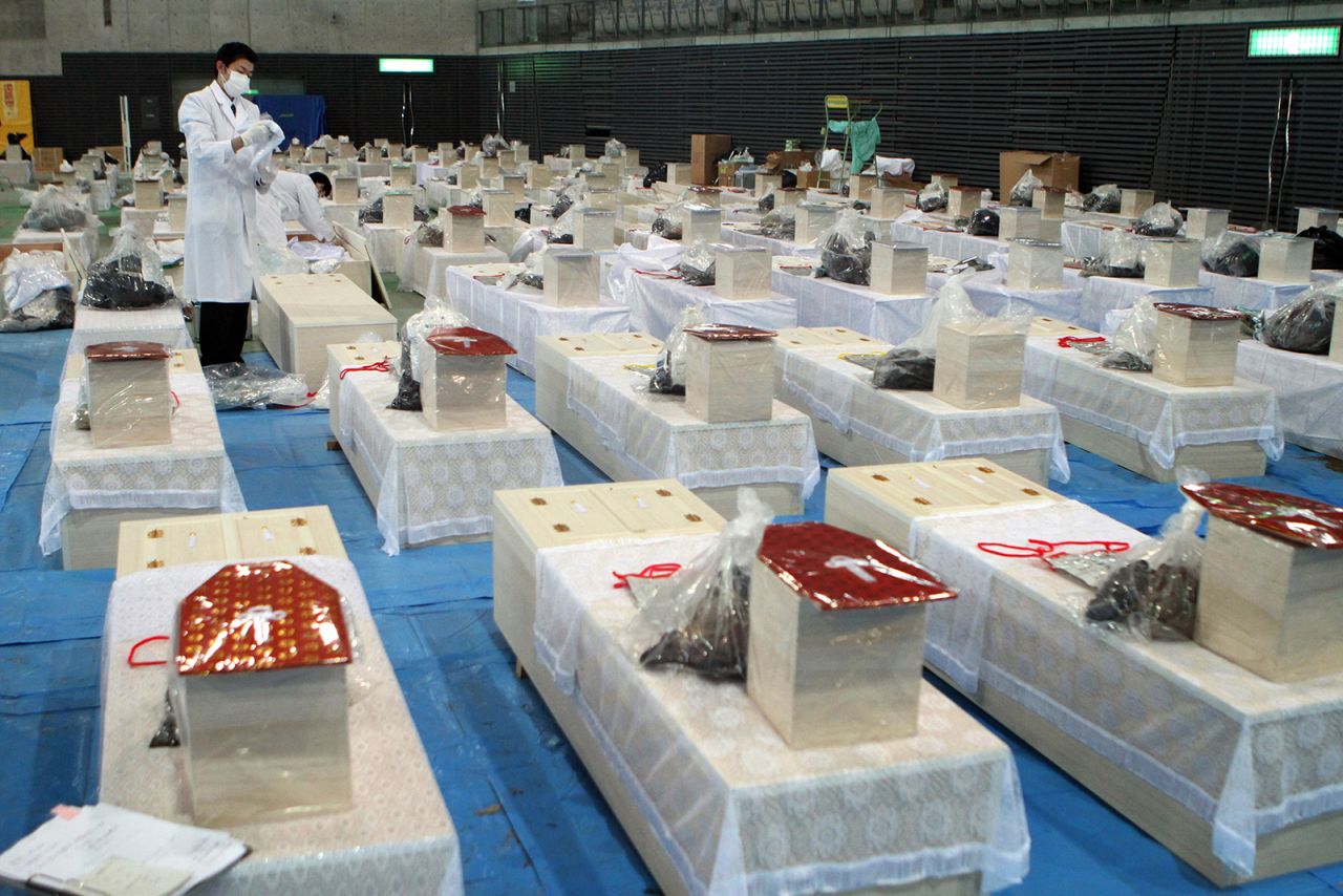 Rows of coffins in Rifu, Miyagi prefecture, carry the remains of people whose bodies were recovered. Others disappeared, swept away by the water that inundated coastal areas.