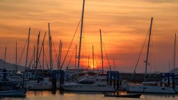 Phuket,Thailand-December 31, 2020: Scene of sunrise and beautiful orange sky at Chalong bay, Phuket, Thailand and row of boats