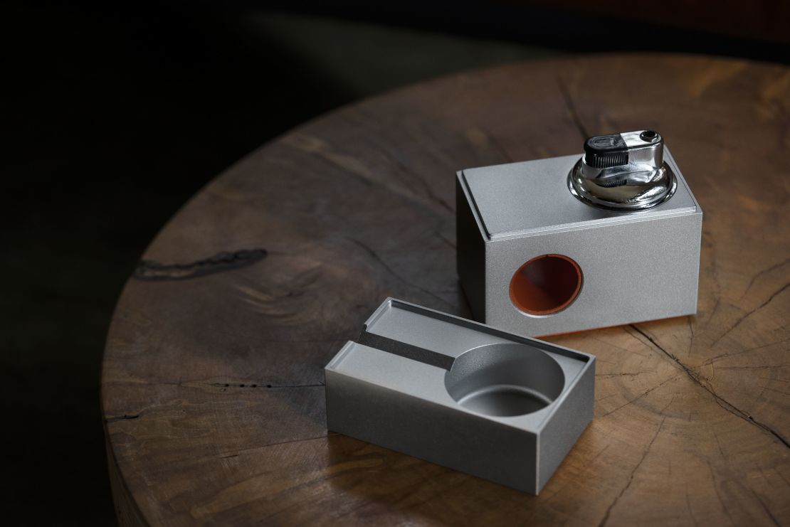 The block table lighter has a lid that can be used as an ashtray and a notch to hold a smoking device.