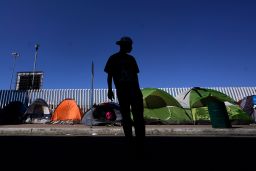 A migrant from Honduras seeking asylum in the US stands near rows of tents at the border crossing on March 1, 2021, in Tijuana, Mexico.