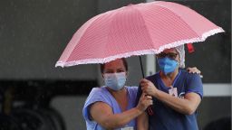 Healthcare workers wait in the rain as a patient suspected of having COVID-19 is brought by ambulance to the public HRAN Hospital in Brasilia, Brazil, Monday, March 8, 2021. (AP Photo/Eraldo Peres)