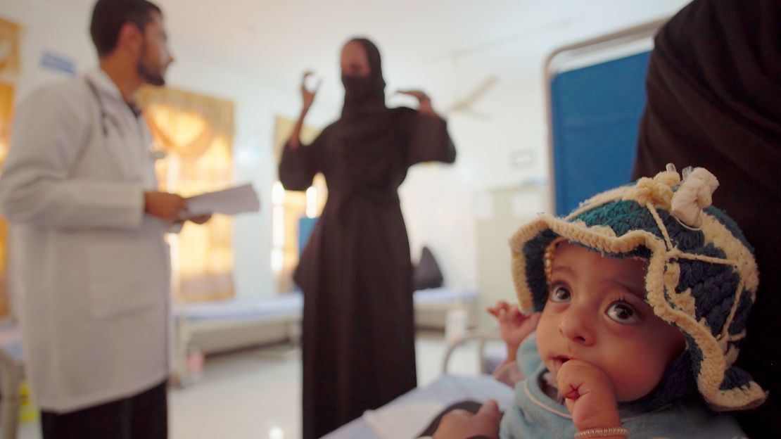 Ten-month-old Zahra sits in her mother's arms at the Rural Harf Soufian Hospital, where she has become a celebrated success story.