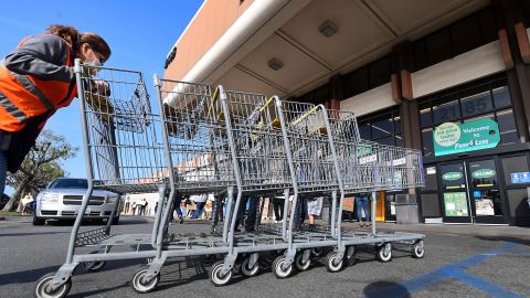 A Food 4 Less employee pushes carts past supermarket workers gathered to protest in front of the supermarket in Long Beach, California on February 3, 2021