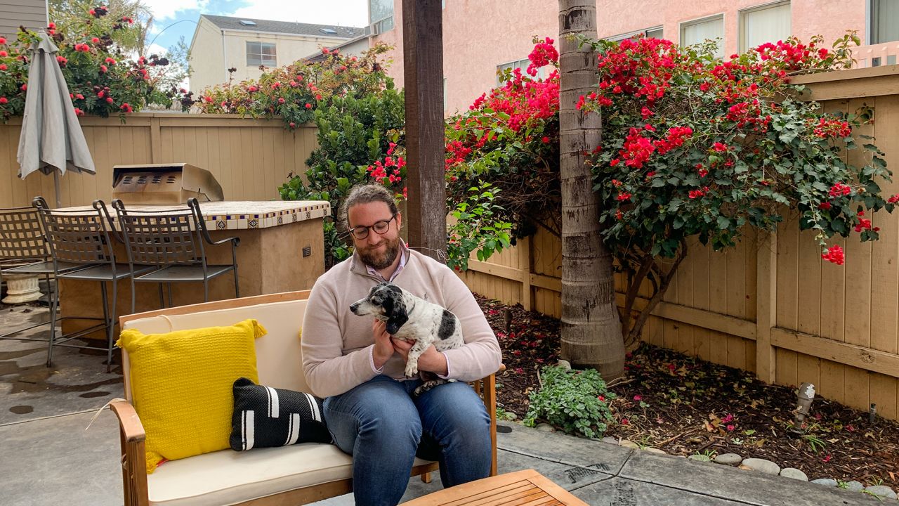 Ryan Mattison holds his roommate's dog in his new home in San Diego. 