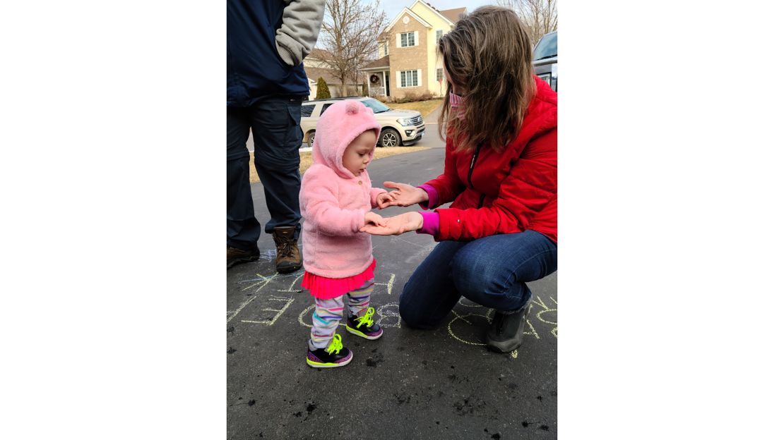 13-month-old Clara curiously touches her grandmother's hands after months of behind-glass visits.