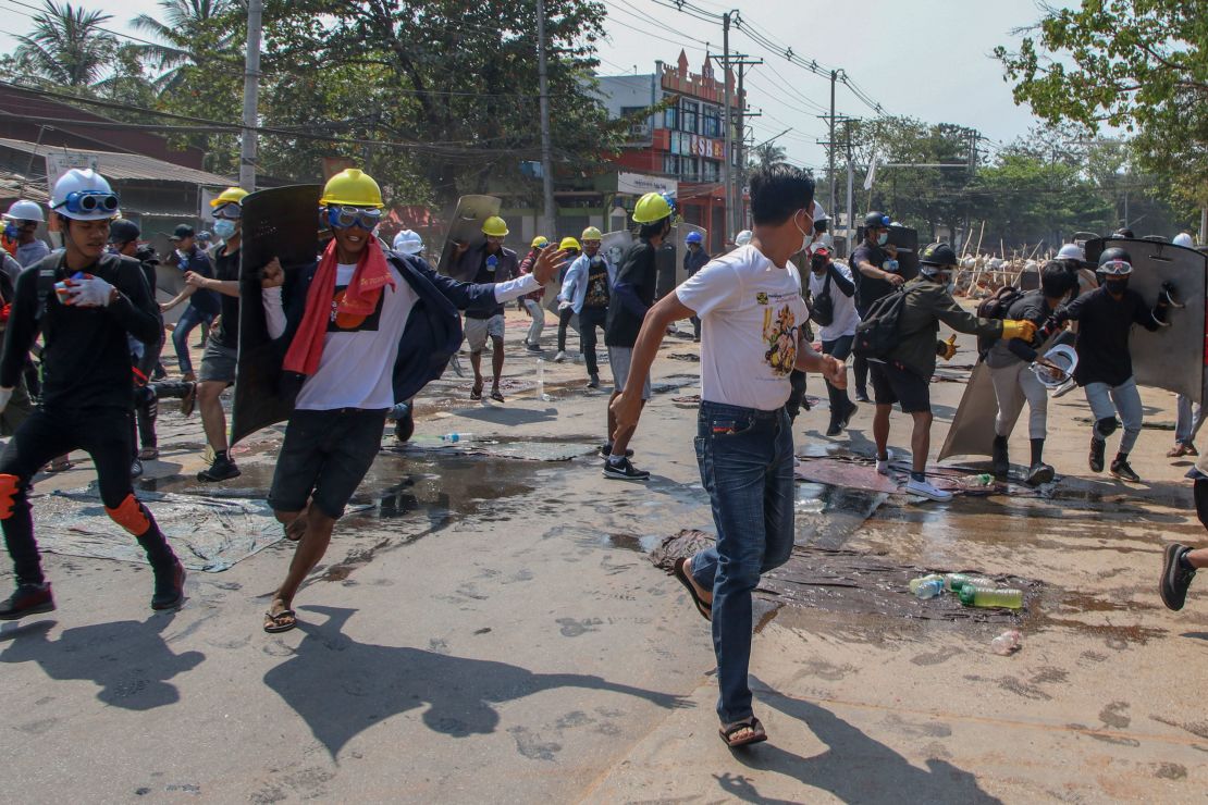Anti-coup protesters retreat from the front lines after riot policemen fire sound-bombs and rubber bullets in Yangon, Myanmar, on March 11.