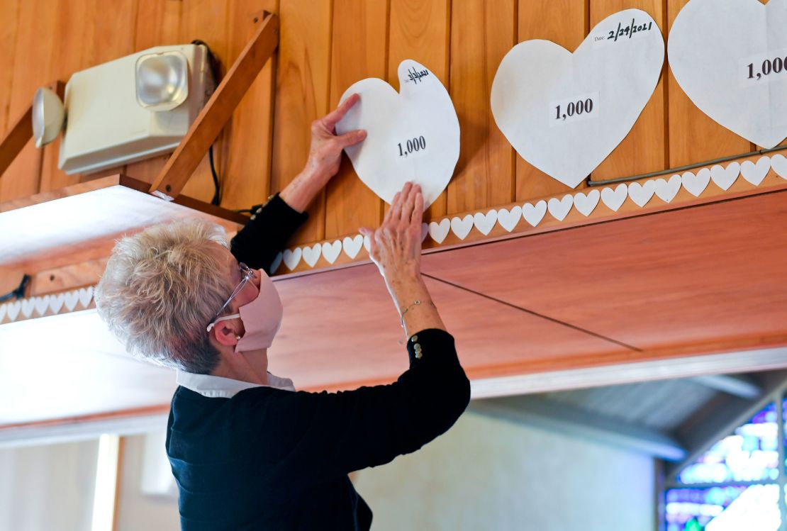 Christy Hylton, church council vice president prepares to put up a paper heart in One United Church of Christ in Kenhorst, Pennsylvania, to represent each 1,000 deaths from Covid-19 in the state on March 3, 2021.