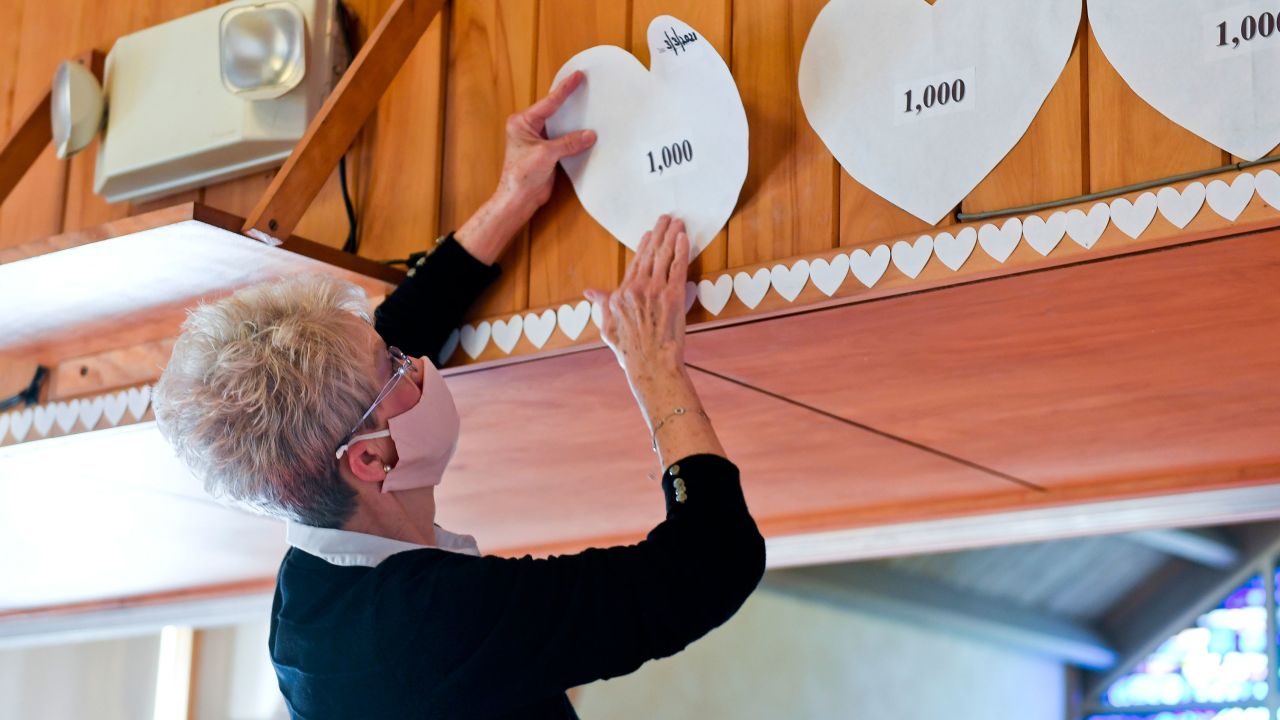 Christy Hylton, church council vice president prepares to put up a paper heart in One United Church of Christ in Kenhorst, Pennsylvania, to represent each 1,000 deaths from Covid-19 in the state on March 3, 2021.