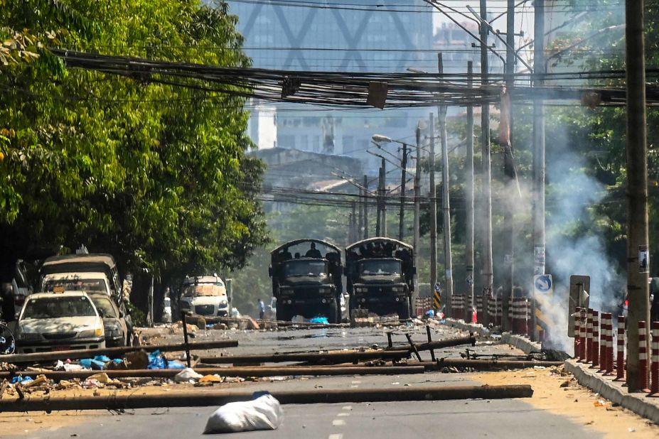 Military trucks are seen near a burning barricade in Yangon that was erected by protesters and then set on fire by soldiers on March 10.