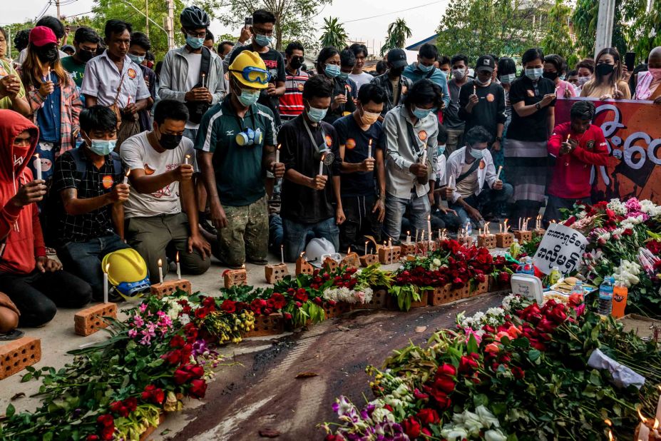 People lay flowers and light candles beside bloodied pavement where protester Chit Min Thu was killed in Yangon.