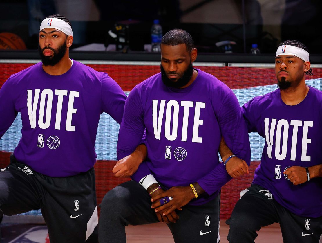 Anthony Davis, LeBron James  Quinn Cook of the Los Angeles Lakers kneel during the National Anthem with VOTE shirts on.
