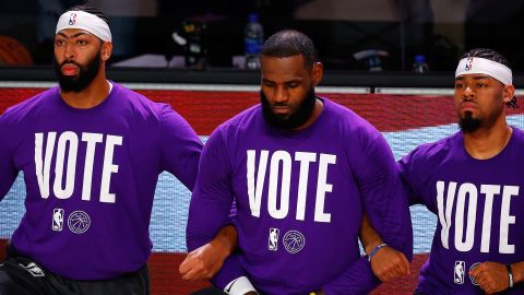 Anthony Davis, LeBron James Quinn Cook of the Los Angeles Lakers kneel during the National Anthem with VOTE shirts on.