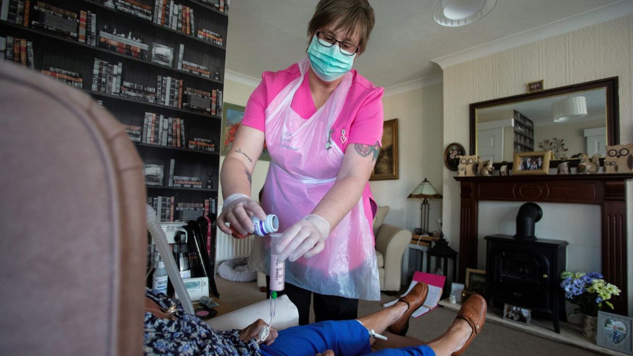 Dawn, a carer from Elite Care Solutions gives her client Tina, who suffers with Multiple Sclerosis and is considered in the high risk category during the current novel coronavirus COVID-19 pandemic, her lunchtime feed via a tube during a home visit in Scunthorpe, northern England on May 8, 2020. - Home carers are an essential key worker service to those with disabilities stranded at home under the lockdown, providing specialist care and human kindness.  Dawn has worked with Tina for seven years and although Tina's disabilities limit her outdoor recreation, she misses most of all her and Dawn's visits to the local park for their weekly latte drink. (Photo by Lindsey Parnaby / AFP) (Photo by LINDSEY PARNABY/AFP via Getty Images)