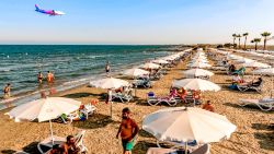 This picture taken on August 1, 2020 shows a Wizz Air Airbus A320-232 aircraft on its descent approach towards Cyprus' Larnaca International Airport as it flies over beachgoers at a nearby beach along the Mediterranean. - British visitors returning to Cyprus -- a former UK colony that depends heavily on tourism -- are set to give the holiday island's tourism sector a welcome boost after a battering by the pandemic, but some locals are sceptical about how big the gains will be. (Photo by Iakovos Hatzistavrou / AFP) (Photo by IAKOVOS HATZISTAVROU/AFP via Getty Images)