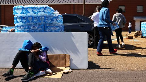A brother and sister sit while their mother volunteers at a water and food distribution drive in Jackson, Mississippi after the city was hit by back-to-back winter storms.