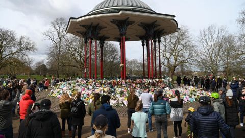 Well-wishers gather beside floral tributes to honor murder victim Sarah Everard on Clapham Common in south London on March 14, 2021.