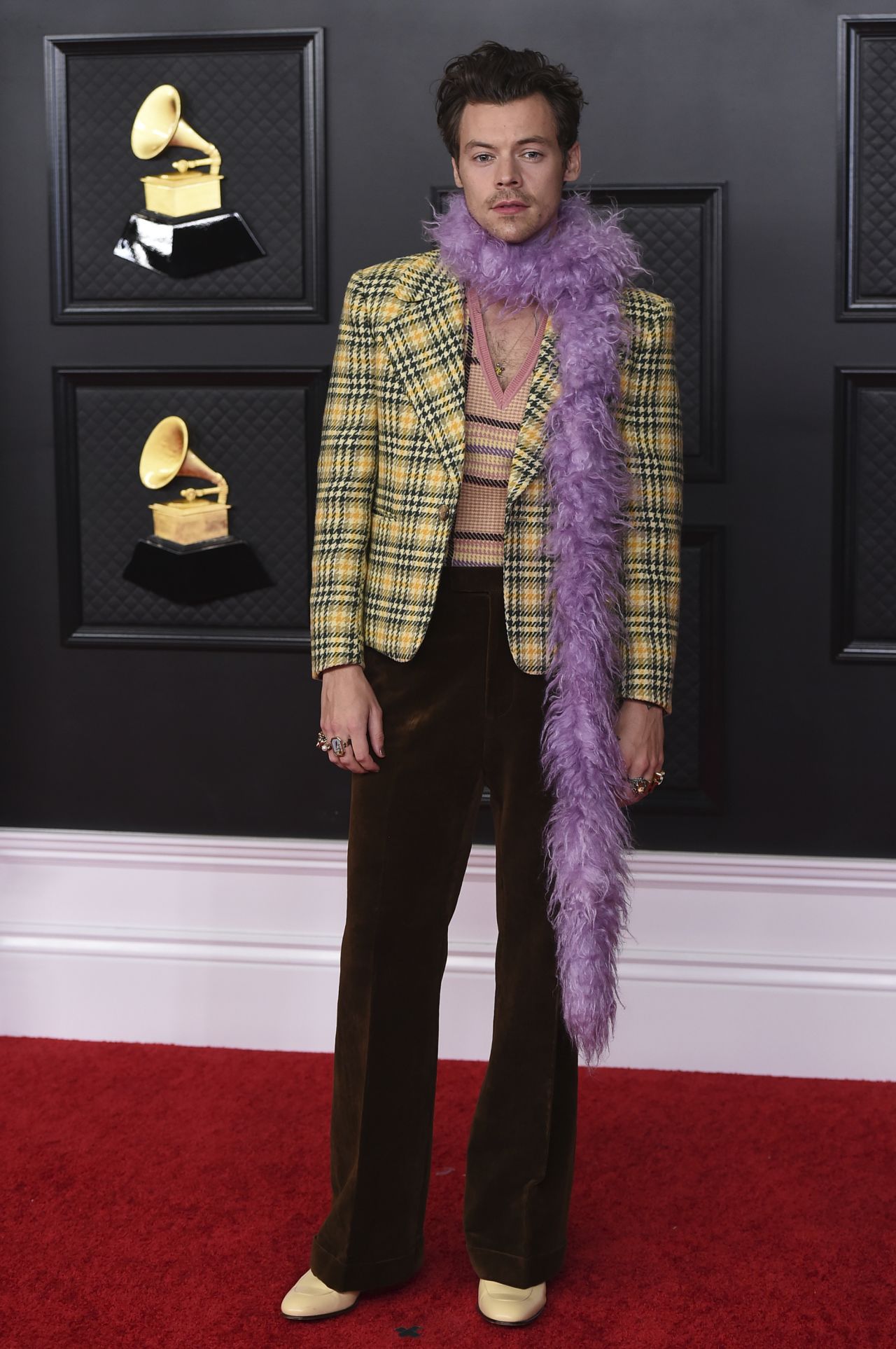 Harry Styles effortlessly paired his yellow plaid suit on the red carpet with a purple feather boa. On stage, he swapped purple for chartreuse. 