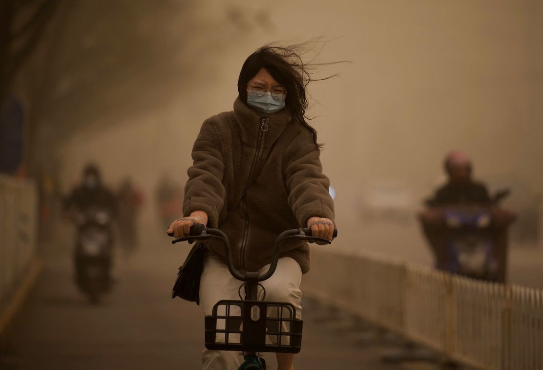 A woman cycles along a street during a sandstorm in Beijing on March 15.