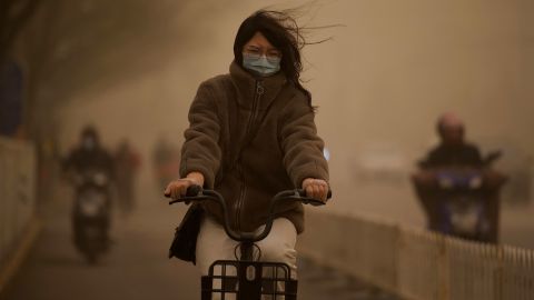 A woman cycles along a street during a sandstorm in Beijing on March 15.