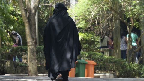 A Muslim woman wearing a burqa walks along a path on the outskirts of Colombo on March 14, 2021.
